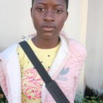 Nzerem Blessing Kamsiriyochukwu, JSS 3 student, standing outdoors in a pink jacket near a wall at the NITDA bootcamp in Enugu