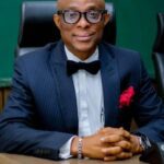 Abimbola Adeseyoju, Founder of DataPro Limited, in a navy pinstripe suit and bow tie, seated at a desk